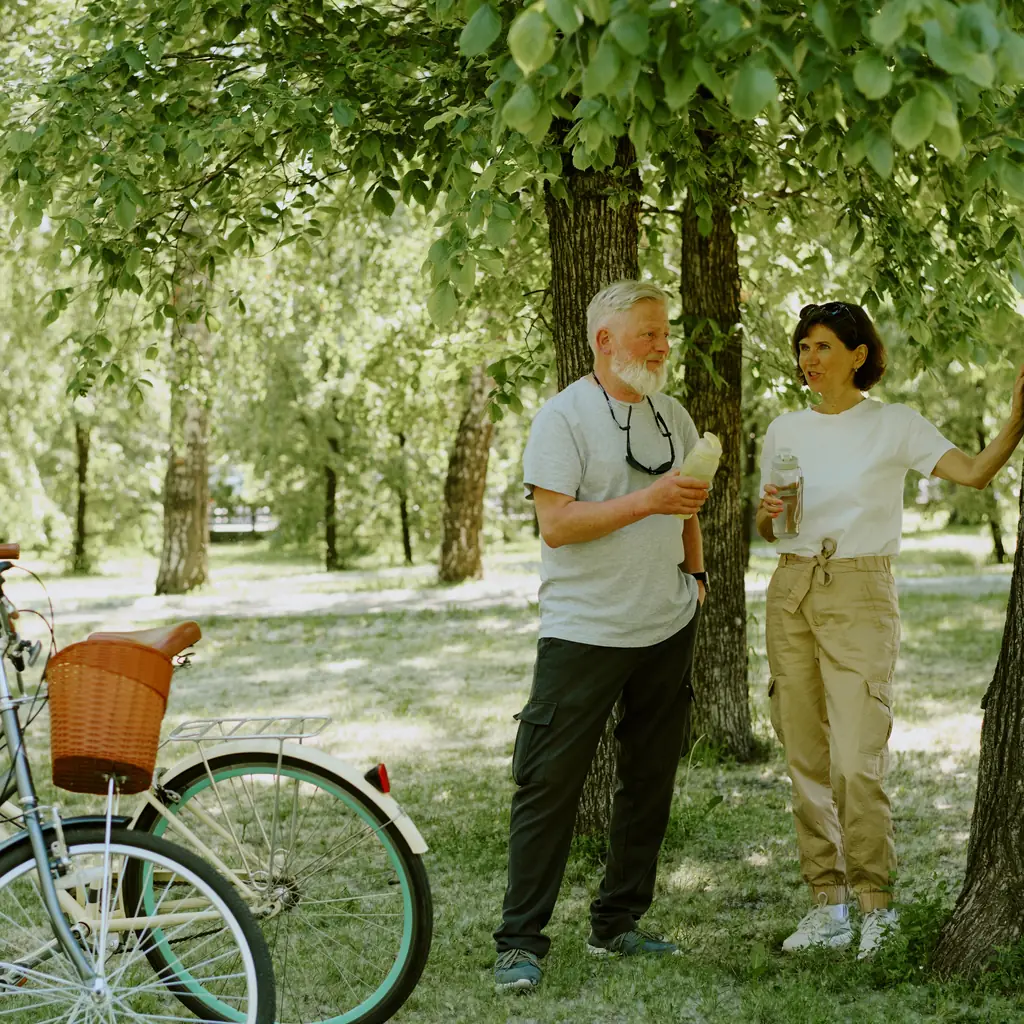 Older cyclists taking a water break at a shaded trail stop